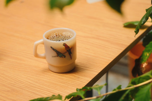 A cup of coffee sitting on a table with leaves around it